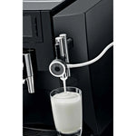 JURA Professional fine‑foam nozzle EA (24251) connected to a black coffee machine, with white tubing and a stream of milk foam into a