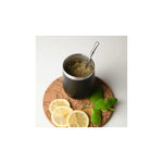Aquafloow Black Yerba Maté thermocup 355 ml with stainless straw, filled with yerba, on a cork coaster with lemon slices