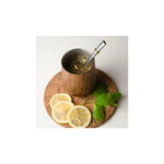 Aquafloow Wooden Yerba Maté thermocup 355 ml with metal straw, filled with yerba, on a cork coaster with lemon slices and mint