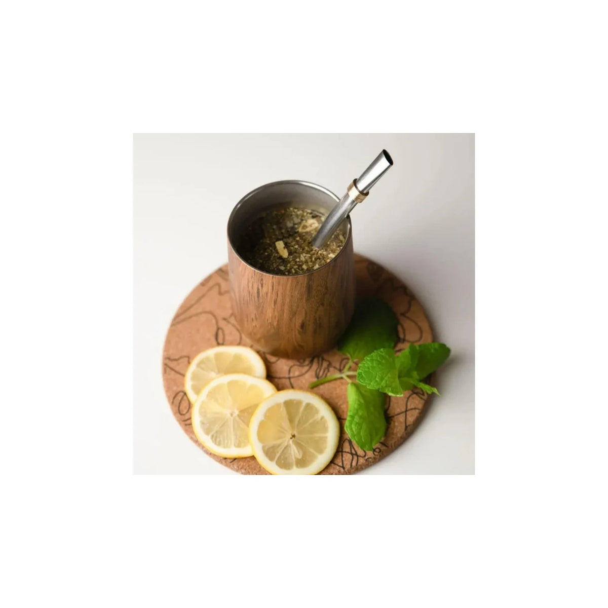 Aquafloow Wooden Yerba Maté thermocup 355 ml with metal straw, filled with yerba, on a cork coaster with lemon slices and mint