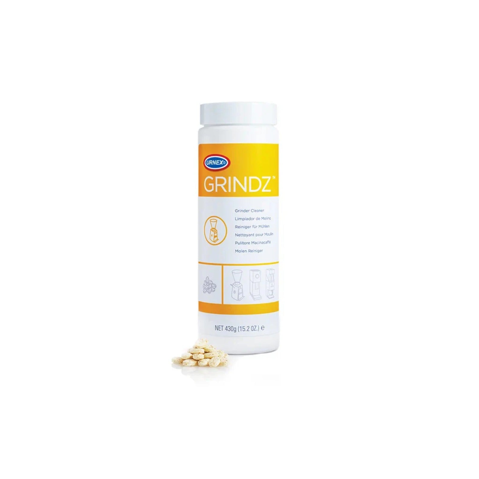White tube Urnex Grindz 430 g with yellow-white label and a pile of cleaning tablets beside it on a white background