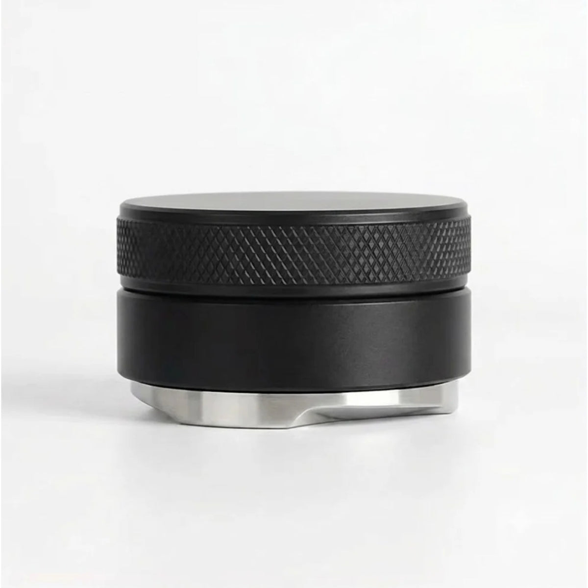 Distributor a zarovnávač kávy v páce 51mm černý kovový disk s vroubkovaným okrajem a nerezovým spodkem na bílém pozadí
